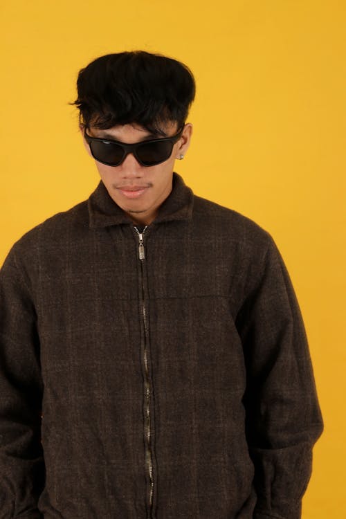 Young Man in a Casual Trendy Outfit Posing in Studio on Yellow Background 