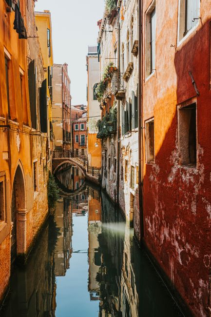 A picturesque view of a narrow canal in Venice with vibrant buildings reflecting in the water.