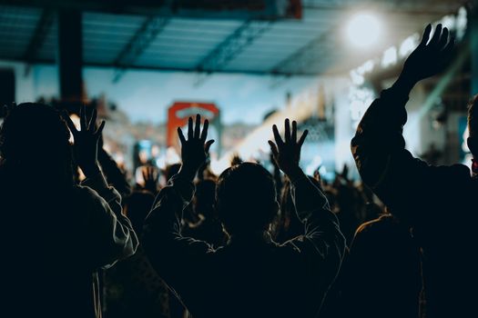 Lively concert atmosphere with people raising hands in Kupang, Indonesia.