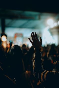 Vibrant night concert scene with a raised hand in Kupang, capturing the lively atmosphere and crowd.