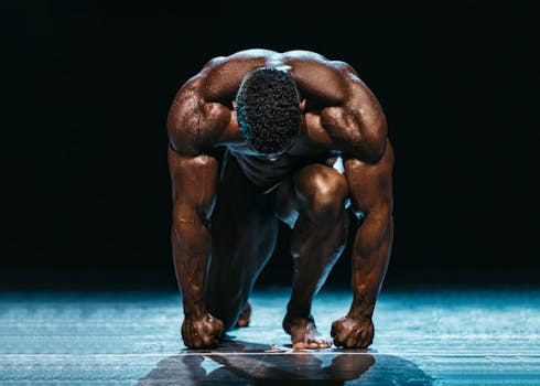 Muscular athlete in a powerful starting position on a dark, dramatic stage.