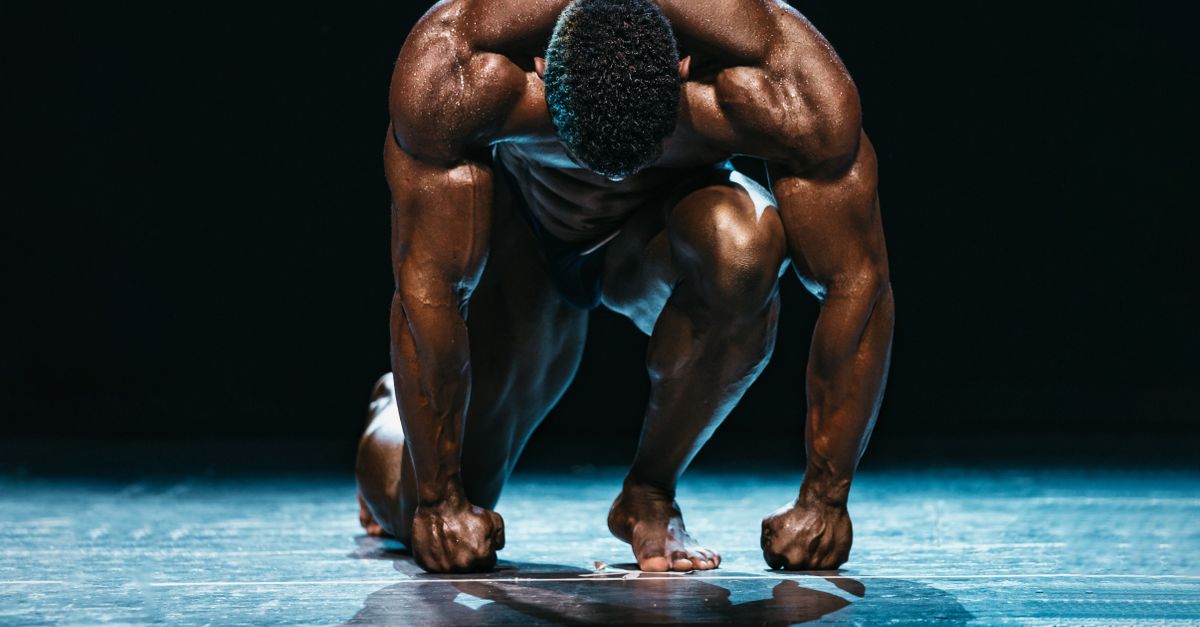 A muscled athlete prepares to start a race on stage under dramatic lighting. - Evidence evidence guide for hmb muscle performance randomized trial