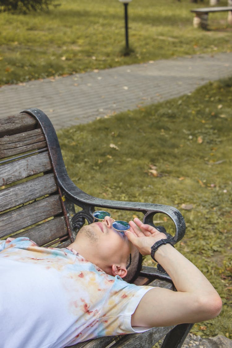 Young Man Lying On Bench In A Park 