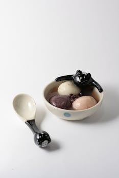 Colorful Taiwanese glutinous rice balls in a playful cat-themed bowl on a white background.