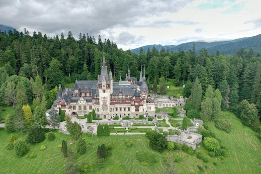 Stunning drone shot of Peles Castle surrounded by lush forest in Romania.