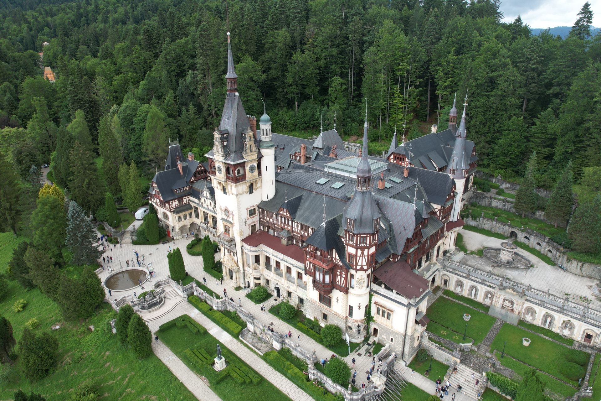 Aerial view of Peleș Castle surrounded by forest in Sinaia.