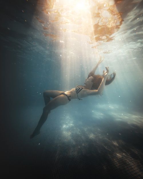 Free A serene underwater scene of a woman in a bikini gracefully illuminated by sunbeams in a Turkish pool. Stock Photo
