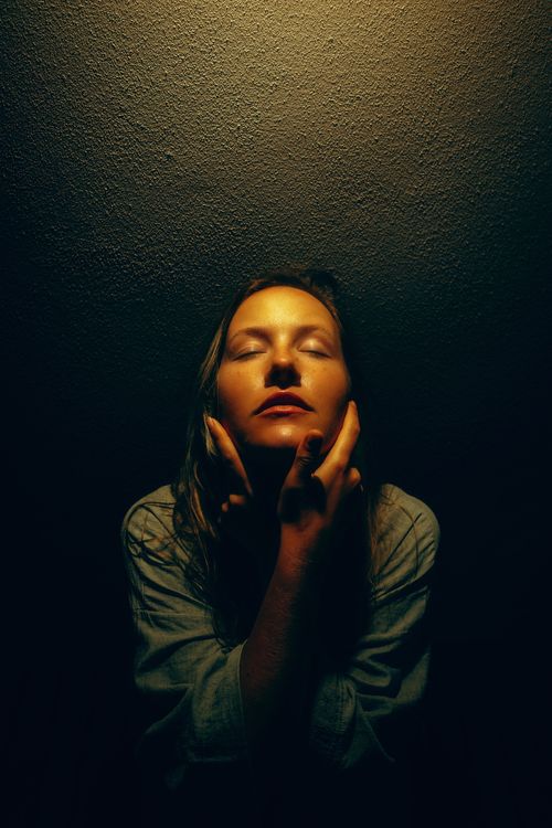 Free A woman with closed eyes in dramatic lighting, evoking a sense of introspection and calm. Stock Photo