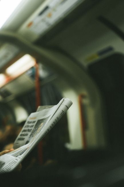 A person reads a newspaper on the London Underground, showcasing urban life in England.