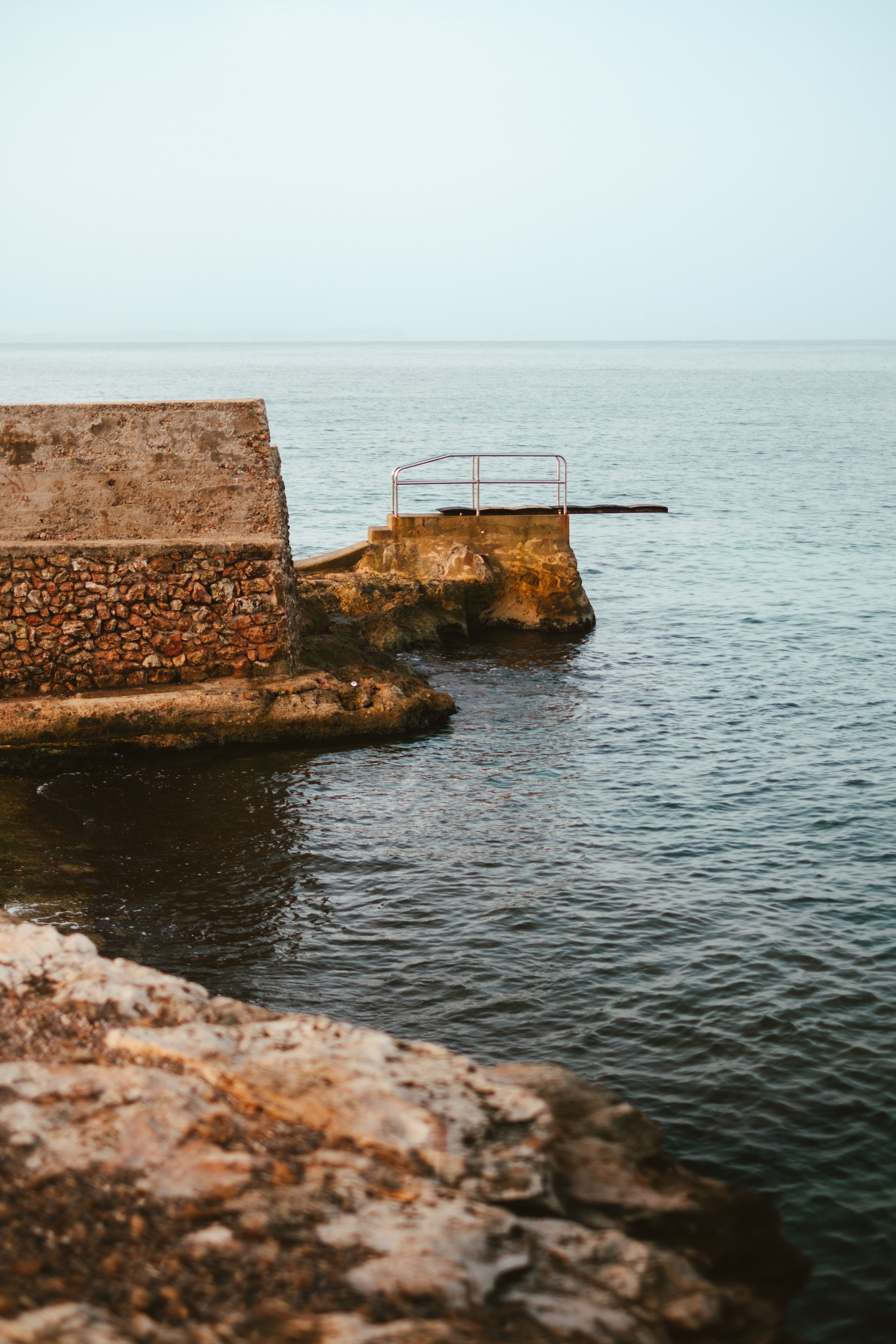 Historic stone platform and sea view in Sa Ràpita, Spain, featuring calm waters and rustic architecture.
