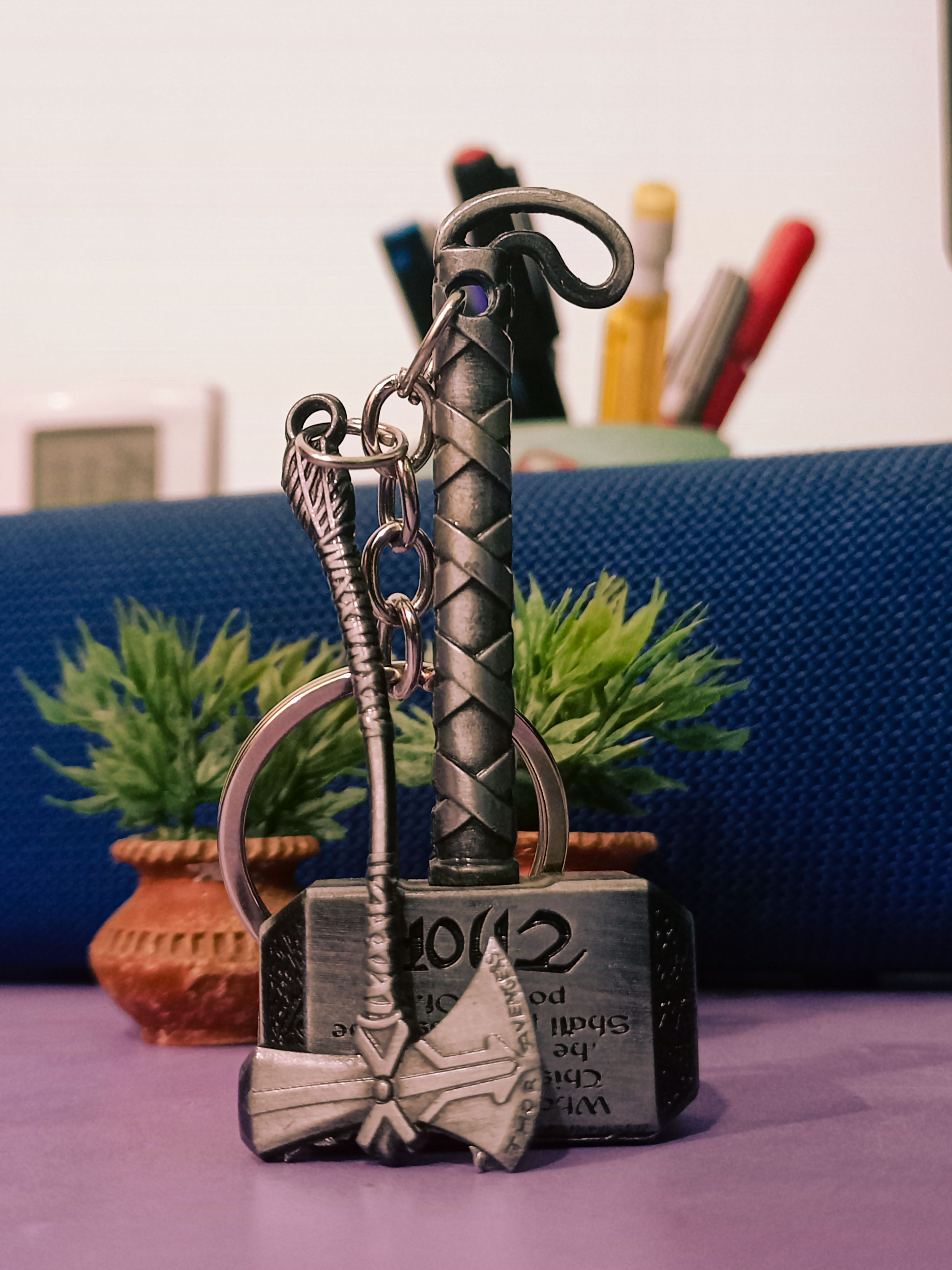 Close-up of a metal keychain with Norse-themed axe and hammer on a table.