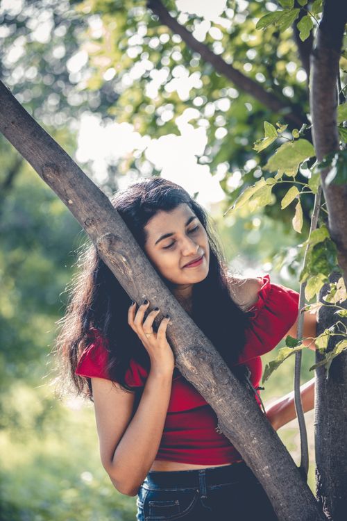 Free Charming young woman enjoying a sunny day, embracing a tree in a Hyderabad park, India. Stock Photo