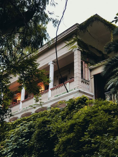 Free A classic colonial mansion with pillars, nestled among vibrant green foliage, showcasing timeless architectural style. Stock Photo