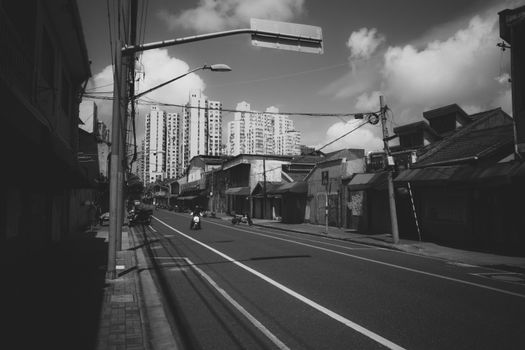 A sunlit urban street with tall buildings in a black and white cityscape.