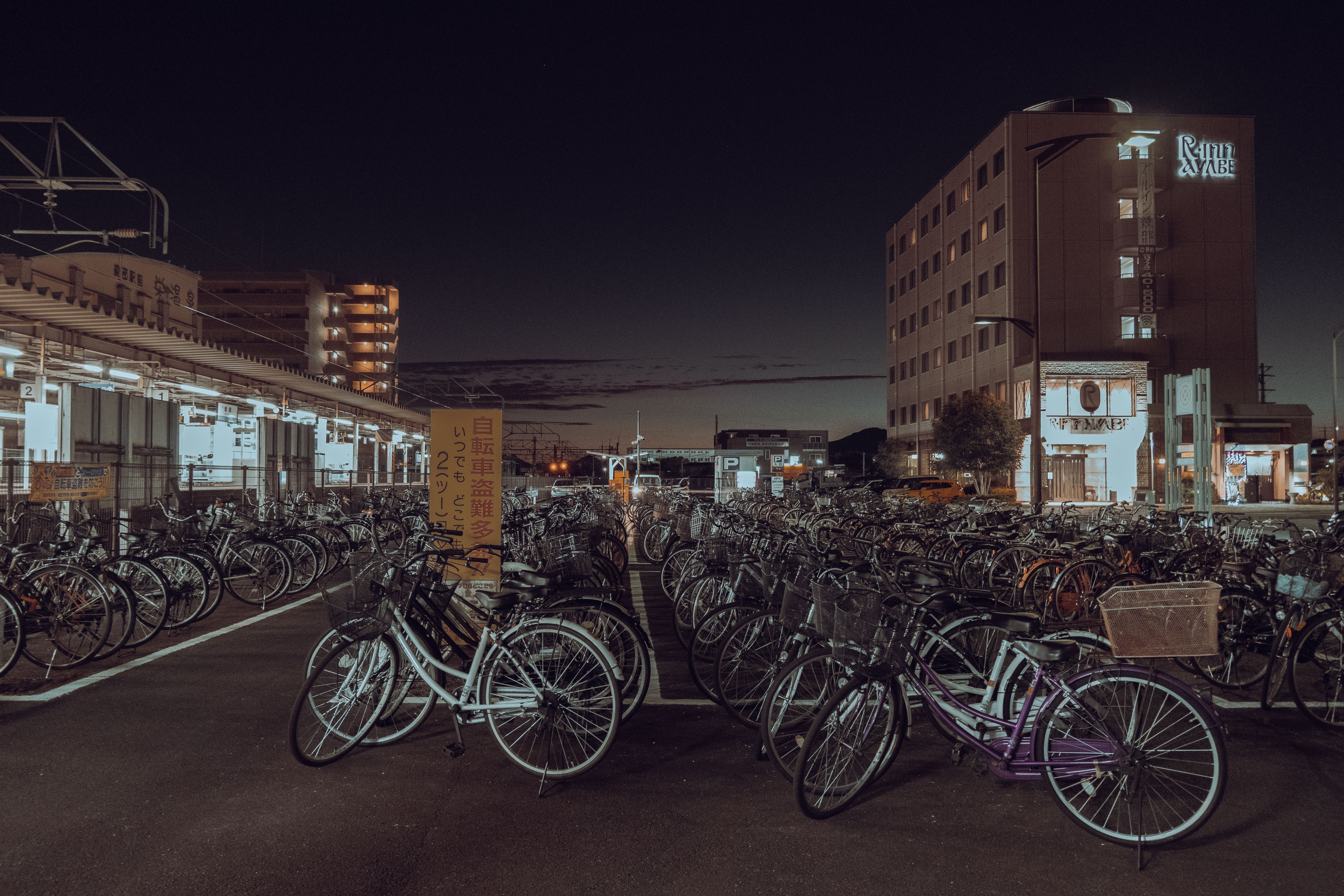 Night view of a bicycle parking lot in urban Kyoto, Japan, showcasing abundance of bikes.