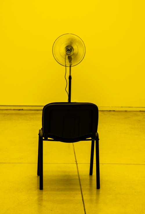 Turned-on Black Pedestal Fan Facing Empty Chair