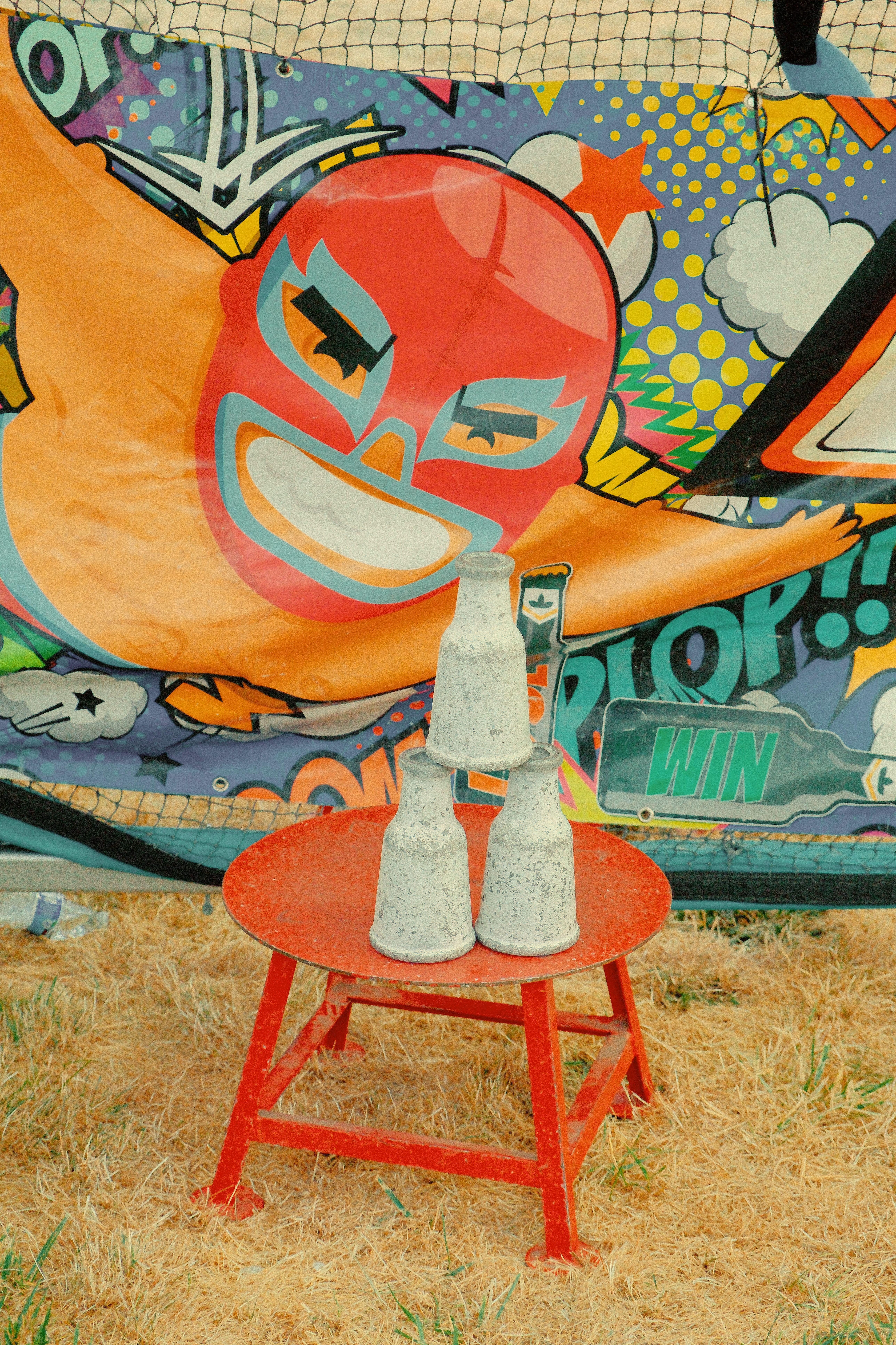 Vibrant carnival scene featuring stacked bottles on a table with playful mural backdrop.