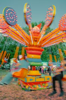 Brightly lit swing ride swirling at a carnival with a vibrant, fun atmosphere.