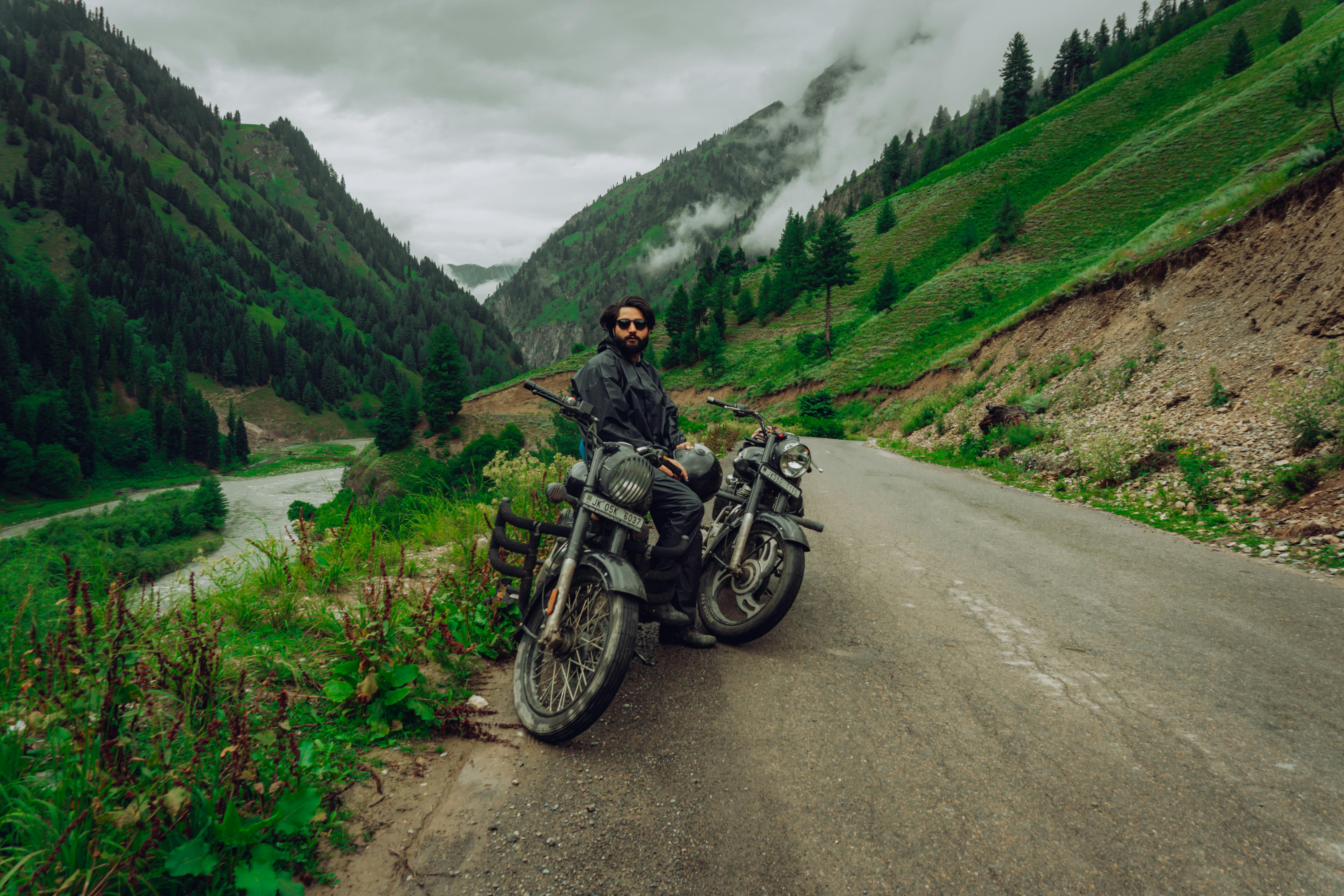 A motorcyclist enjoys a scenic ride in the lush green Gurez Valley, perfect for adventure enthusiasts.