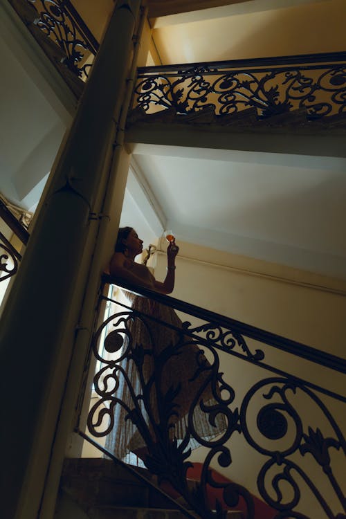 Woman with Wineglass in her Hands Stands on Stairs