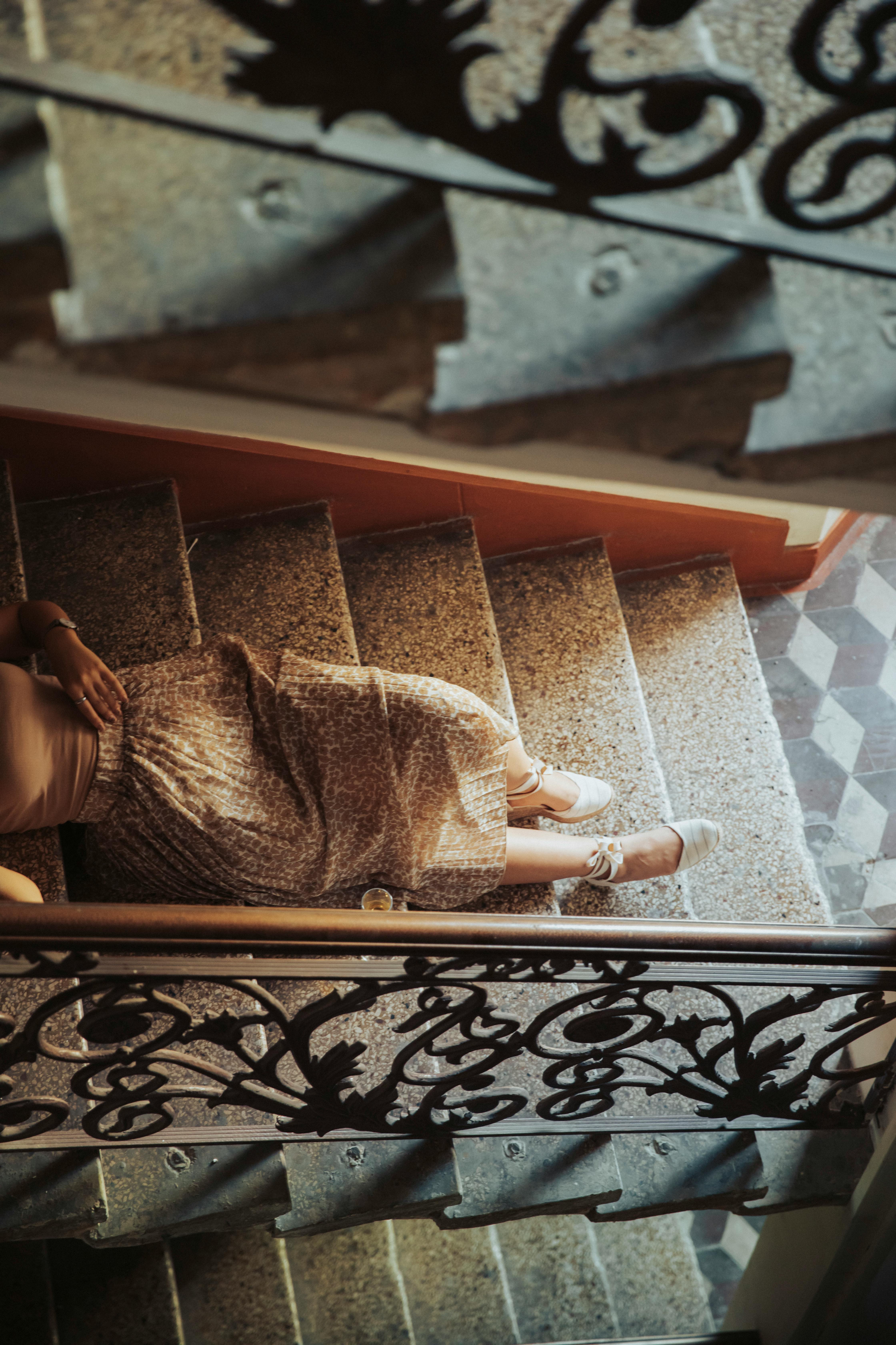 An artistic shot of a woman lying on an ornate staircase in Baku, offering a sense of vintage elegance.