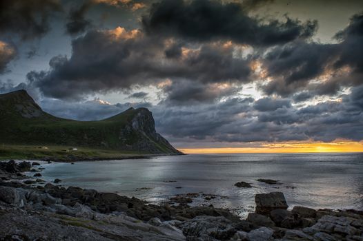 A breathtaking view of a dramatic sunset over a rocky coastline with a dramatic sky.