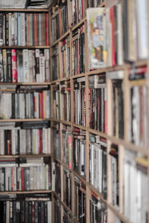 Free A narrow aisle of a used bookstore lined with shelves packed with books. Stock Photo