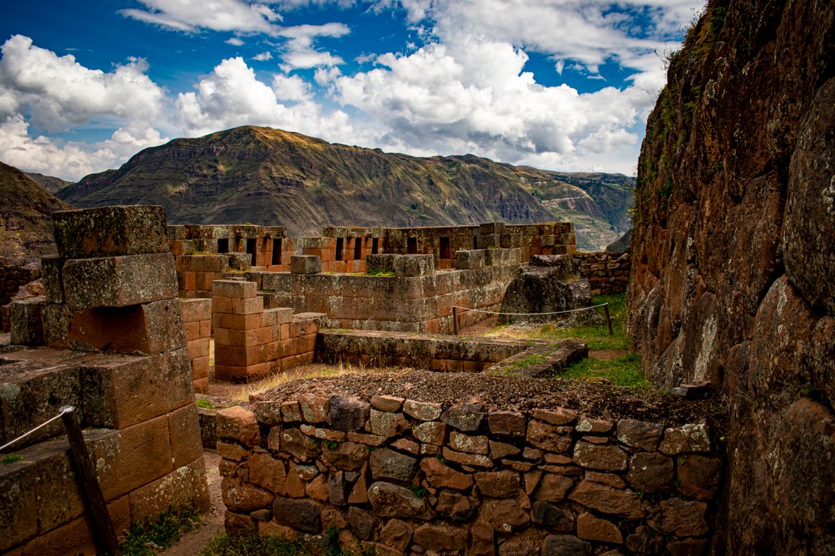 Ancient stone terrace walls at Pisac climbing a steep hillside with the Andes and clouds behind