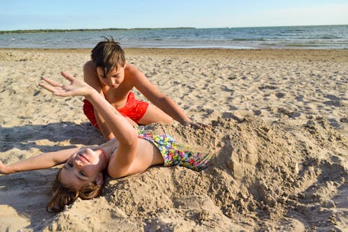 Foto profissional grátis de adolescente, agachado, areia