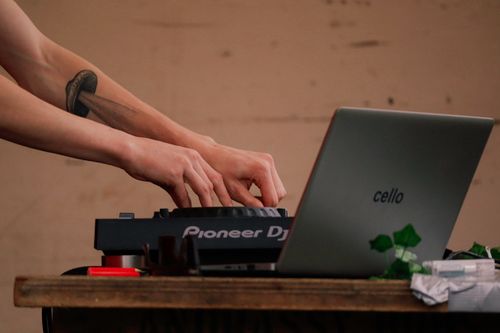 Free Close-up of hands mixing music using a Pioneer DJ controller next to a laptop. Stock Photo