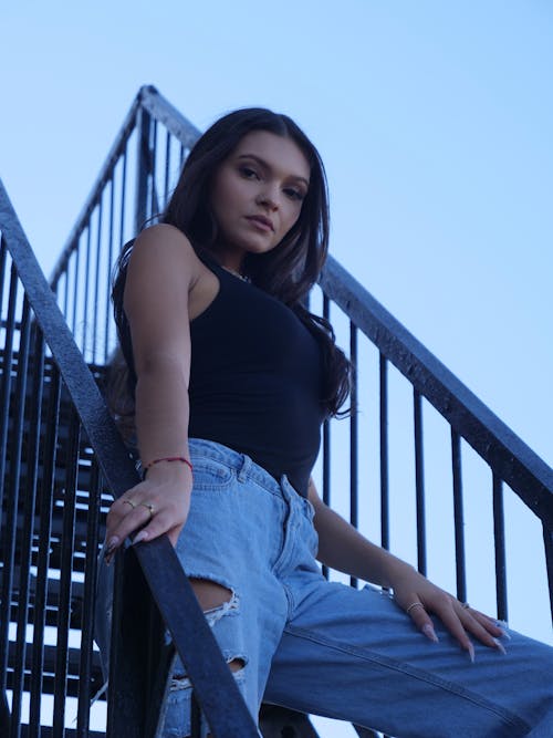 Model in a Black Tank Top and Distressed Jeans Posing on Stairs