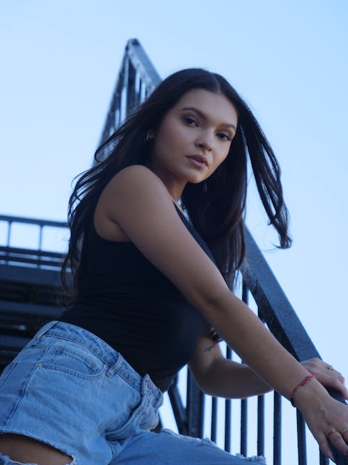 Young Model in a Black Tank Top and Jeans Posing on the Stairs