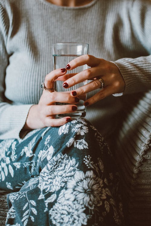 Free Person Sitting on Grey Sofa While Holding Clear Highball Glass of Water Stock Photo