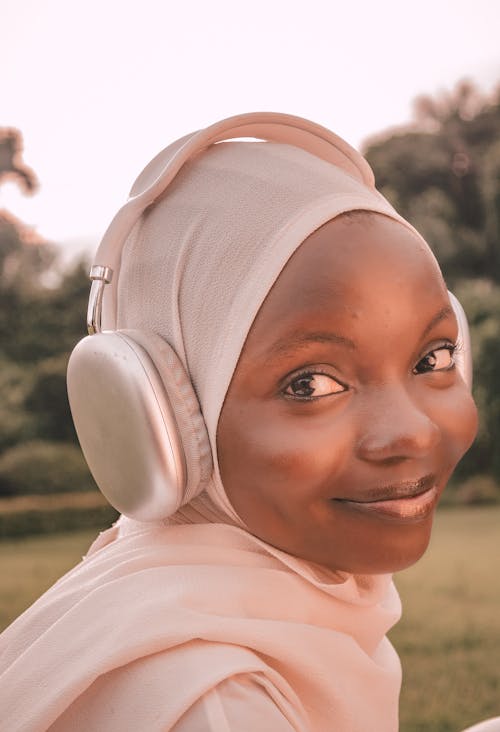Smiling Woman in a White Headscarf and Silver Wireless Headphones