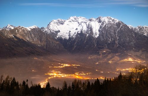 Free Breathtaking view of a snow-capped mountain range with city lights glowing in the valley below. Stock Photo
