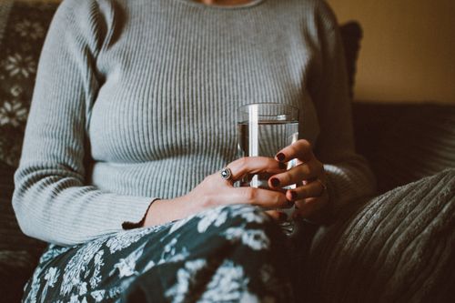 Free Close-up of a woman holding a glass of water while sitting indoors, conveying calm and relaxation. Stock Photo