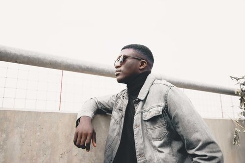Free Fashionable man wearing sunglasses and denim jacket posing against an urban backdrop in Abuja. Stock Photo
