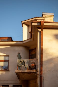 A small balcony on an apartment building, bathed in warm summer sunlight.