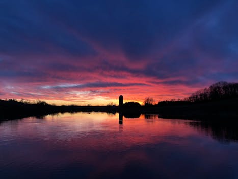 Beautiful silhouette and vibrant sky colors over a tranquil rural lake at sunset.