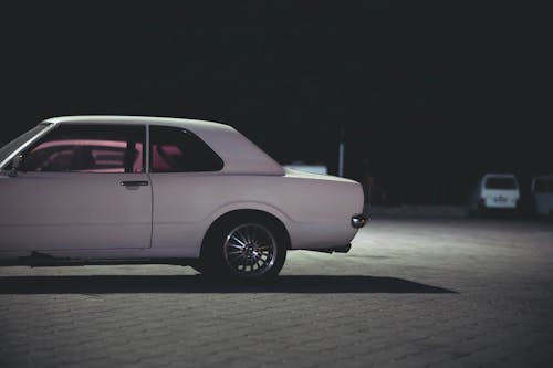 View of a Vintage White Car Parked on a Parking Lot at Night 