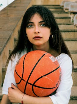 A woman holding a basketball while sitting outdoors on steps in Baku, Azerbaijan.