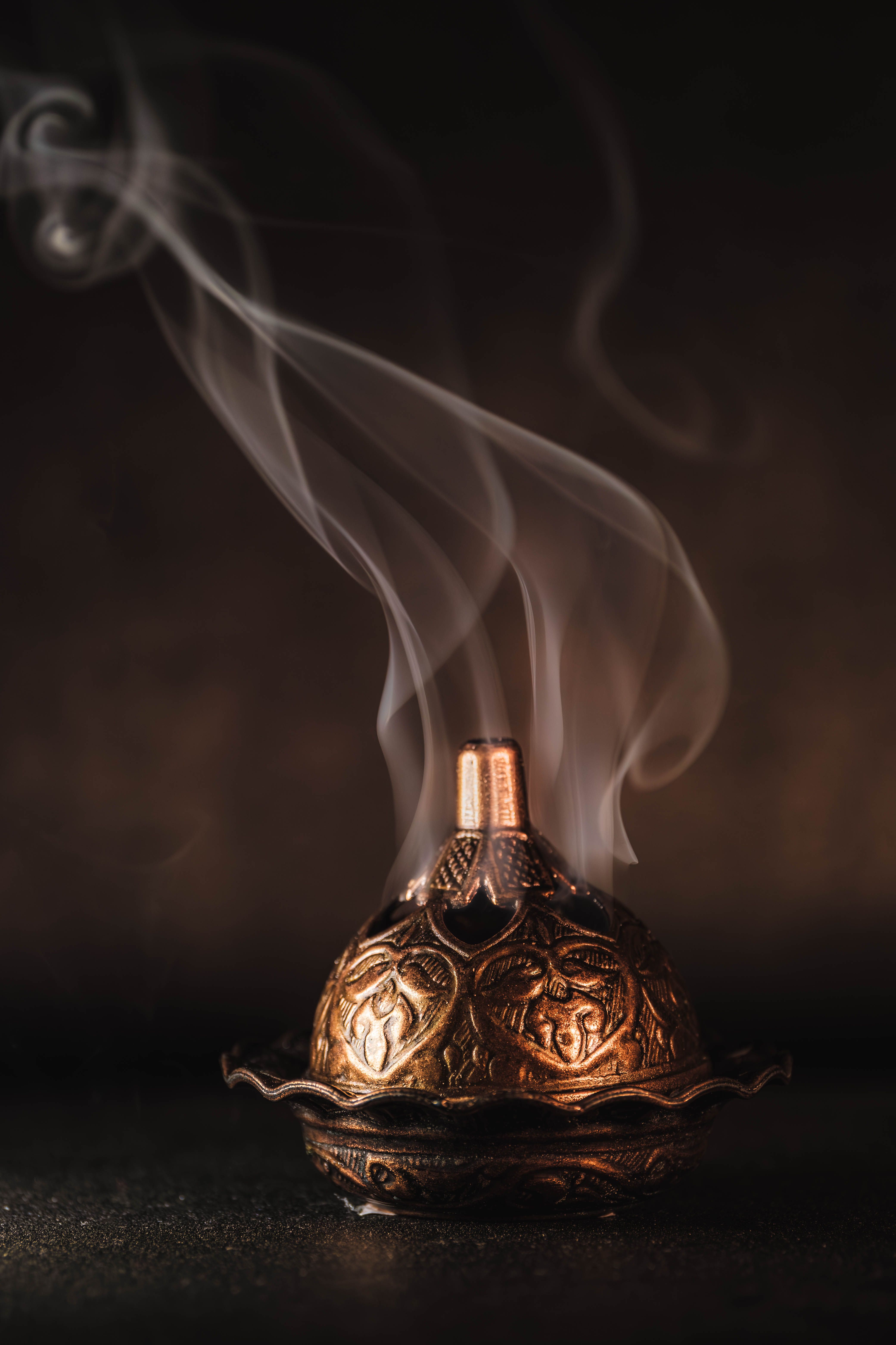 A beautifully detailed incense burner with ornate patterns and rising smoke, creating a calming atmosphere.