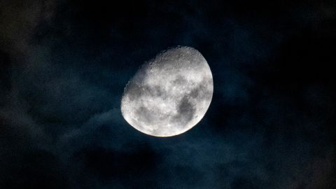 A captivating view of the gibbous moon shining through dark clouds in the night sky over Rio de Janeiro.