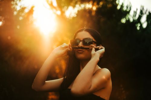 Free A young woman with sunglasses, making a mustache with her hair in sunlight. Stock Photo