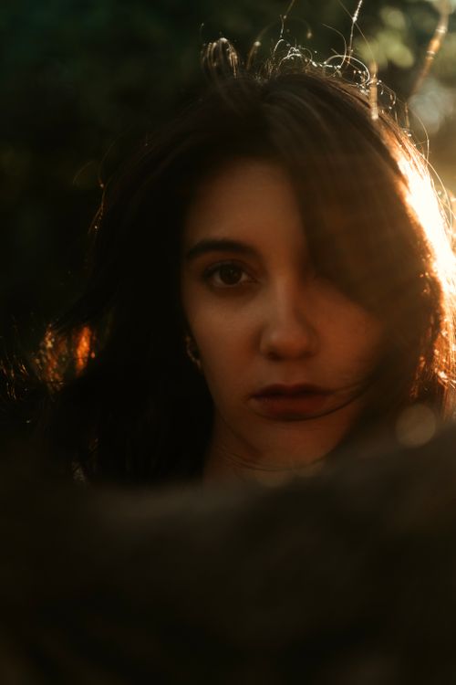 Free Artistic portrait of a woman with dramatic lighting and warm tones, creating an intense, moody effect. Stock Photo