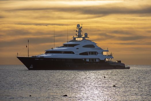 Stunning view of a luxury yacht sailing at sunset in Cabo San Lucas, Mexico's tranquil waters.