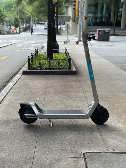 An Electric Scooter Parked on a Sidewalk in City 