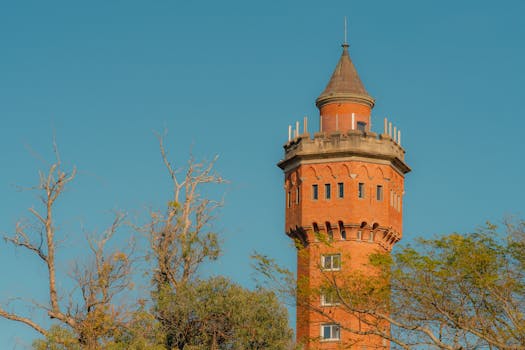 A historic brick tower in Maldonado, Uruguay, against a clear blue sky, framed by trees.