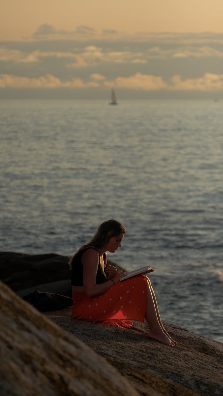 Woman Sitting On The Beach And Reading A Book 