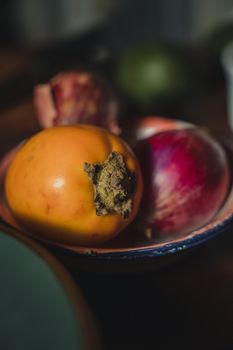 Fresh persimmon and red onion in a rustic bowl, perfect for organic food themes.